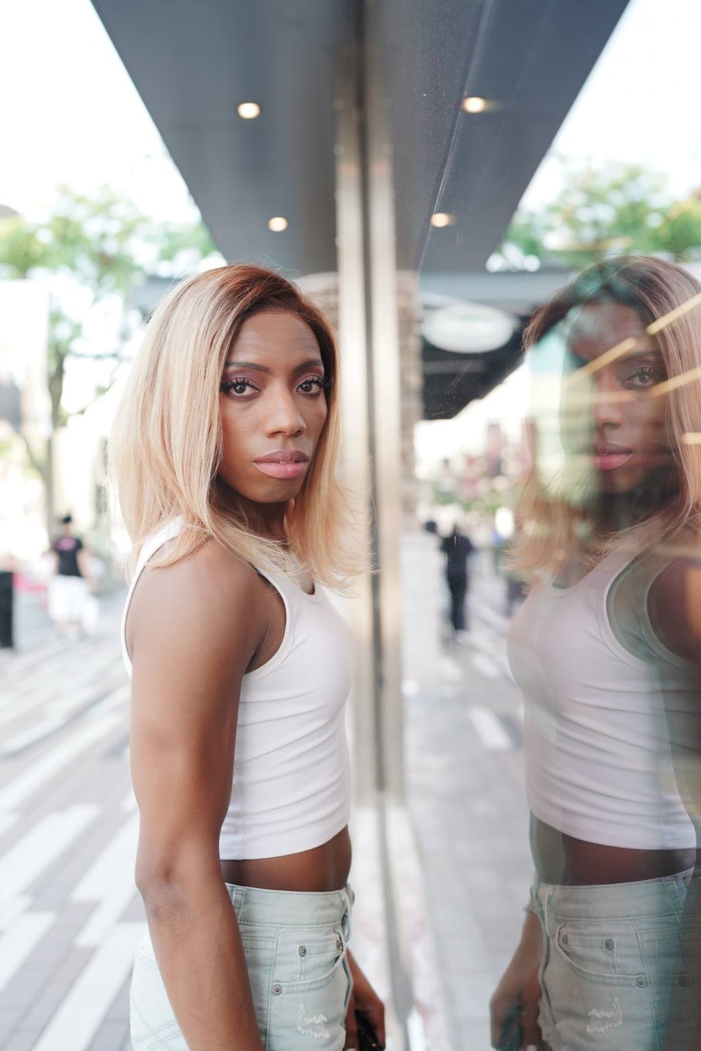 Editorial portrait of a woman mirrored in a city storefront window